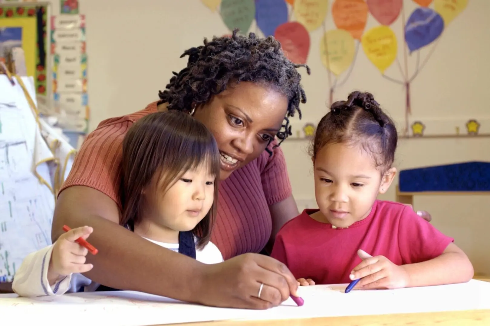 Woman teaching drawing to two toddlers